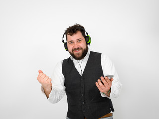 cool man with black beard and white shirt is posing with headphones and smartphone in front of white background