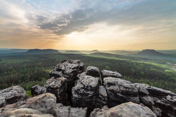 Elbe Sandstone Mountains - panoramic view from the mountain Gohrisch to the west, evening light with sunbeams and light haze, in the foreground sandstone cliffs - Germany, Saxony, Saxon Switzerland