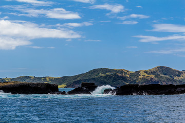 Fototapeta na wymiar Waves crash against the rocks, Bay of Islands, New Zealand
