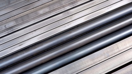 Diagonal view of carbon steel pipes and many rectangular steel tubes on the floor for background design in construction and industrial concept, top view with copy space