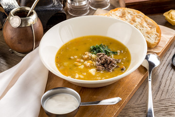Fresh homemade vegetable soup with peas, potatoes garnished with fresh parsley and meat on rustic wooden board