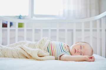 Baby sleeping in co-sleeper crib attached to parents' bed