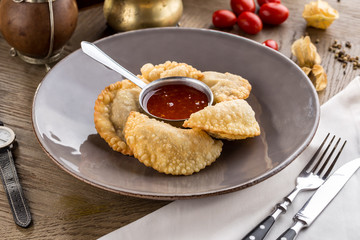 Fried dumplings with tomato sauce on plate on wooden table