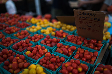 Fresh tomatoes on farmers market, California, USA. Pint baskets of organic colorful tomatoes on the counter at a farmers market. Organic vegetable stall. Selling fresh vegetables. Bio and eco food.
