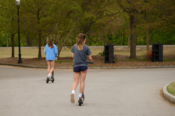 Girls Riding Electric Scooters in Park