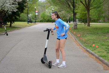 Naklejka premium Girl Riding Electric Scooter in Park