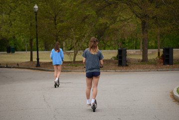 Girls Riding Electric Scooters in Park