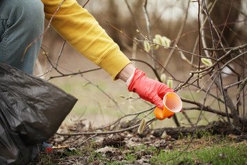 Obraz premium Hand of volunteer lift off litter ground. Spring cleaning in nature, outdoor trash and rubbish.