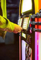 Male hand pushing buttons to play song on old Jukebox, selecting records