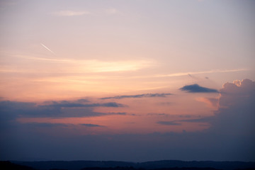 Sunset in the austrian alps with silhouette of colorful clouds in front of the horizon