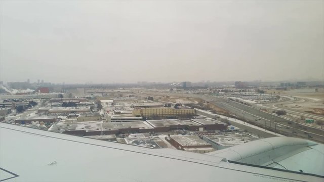 Looking out plane window at winter plane landing at Toronto. Person airport with snow view from window as airplane touches down on runway in smooth approach over highway in dangerous conditions.