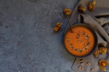 Pumpkin soup in a bowl with autumn vegetables and pumpkin seeds. Vegan soup. Vegetables cream soup and ingredients. Top view. Concept of healthy eating or vegetarian food. Top view with copy space.