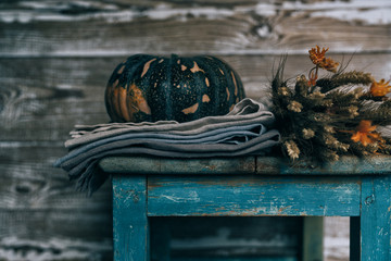 Ears of golden wheat, apples and pumpkins on rural weathered wooden stool on barn boards background. Vintage seasonal autumn decorative background with fall vegetables. Harvest time concept.