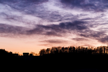 Fototapeta premium colorful sunset with glowing clouds and a tree a hill and valley silhouette in the austrian alps
