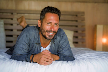 30s happy and handsome man at home in casual shirt and jeans lying on bed relaxed at home smiling confident and happy feeling positive in male lifestyle concept