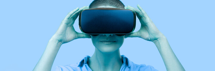Young woman wearing virtual reality goggles. Woman wearing VR glasses over blue background. VR...