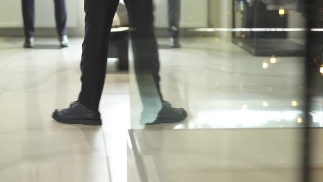 A client walking in showroom of men clothing boutique with stylish interior and looking through male suits. Boutique of brand male clothes