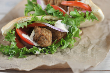 Falafel in pita bread with tomatoes, lettuce and sauce occupies the entire frame space. Background craft paper. Close-up. Macro shooting. View from above.