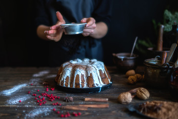 Cooking homemade cake Christmas Eve at home rustic kitchen. Woman's hands make pudding. Ingredients for cooking christmas baking on dark wooden table. Merry Christmas and Happy Holidays! Toned image.