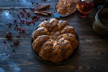 Holiday cake on wooden table with berry, spice and chocolate at rustic home kitchen. Christmas baking background. Ingredients for cooking on dark wooden background. Homemade festive food. Toned image
