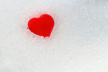 Red heart in the snow. Close-up. Background. Texture.