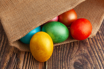 Colorful Easter eggs on a wooden background in burlap