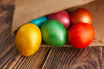 Colored Easter eggs on a wooden background in burlap