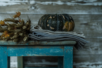 Ears of golden wheat, apples and pumpkins on rural weathered wooden stool on barn boards background. Vintage seasonal autumn decorative background with fall vegetables. Harvest time concept.