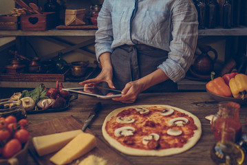 Cook hands. Close up on hands, some ingredients around on table. Fresh original Italian raw pizza, preparation in traditional style. Ingredients and spices for making homemade pizza on wooden table.