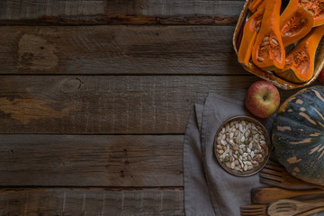 Fresh organic vegetables on rustic wooden background. Healthy natural food. Sliced and whole pumpkins with seed. Cooking ingredients. Autumn seasonal eating. Rural still life. Top view. Toned image.