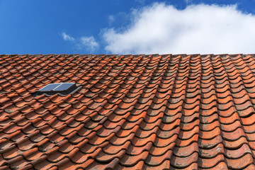 An old roof with burnt tiles. Roof in village house against a blue sky background