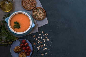 Pumpkin soup in a bowl with autumn vegetables and pumpkin seeds. Vegan soup. Vegetables cream soup and ingredients. Concept of healthy eating or vegetarian food. Top view with copy space. Toned image.