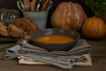 Obraz na płótnie Canvas Homemade autumn butternut squash soup with bread. Roasted pumpkin and carrot soup with cream and pumpkin seeds on white wooden background. Concept of healthy eating food. Copy space. Toned image.