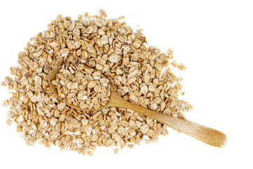 Pile of wheat flakes and wooden spoon