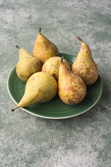 group of ripe pears in green porcelain dish on green marbling background