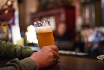 man's hand holds a glass of beer in bar 