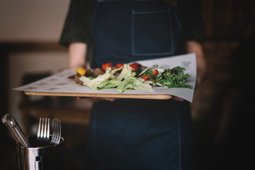 Waiter serving salad and grilled meat at restaurant, close up view. Eating and leisure concept. Toned image. Selective focus.