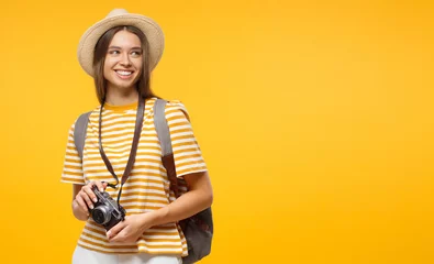 Fotobehang Horizontal banner of smiling young female tourist holding camera, isolated on yellow background with copy space © Damir Khabirov