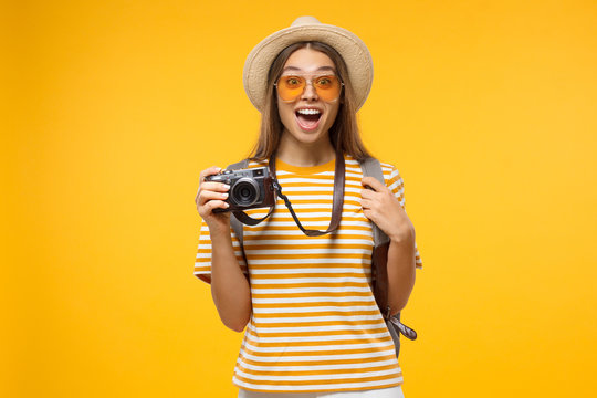 Travel concept. Young female student traveller  holding photo camera, isolated on yellow background.