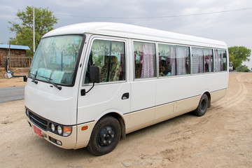 The small bus stands on a stop along the road to Mandalay, Myanmar. White express bus ready for departure, Burma.