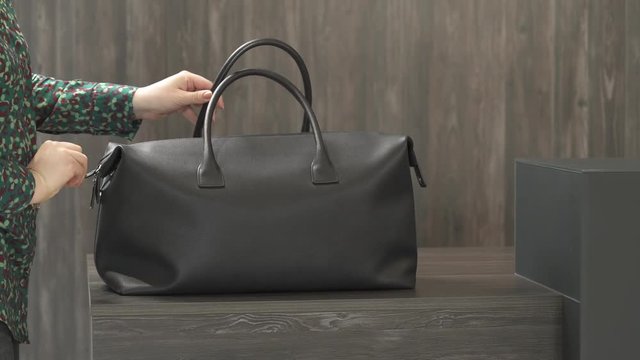 A woman closing zipper of her beautiful black leather purse and taking it away. Close-up demonstration video