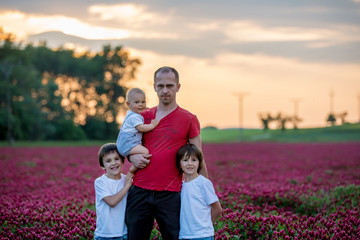 Father, having his portrait with his three sons, boys, in crimson clover field on sunset