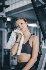Young attractive woman caucasian sitting and using towel to wipe the sweat. Relaxation after hard workout in gym. Fitness concept, Healthy, Sport, Lifestyle