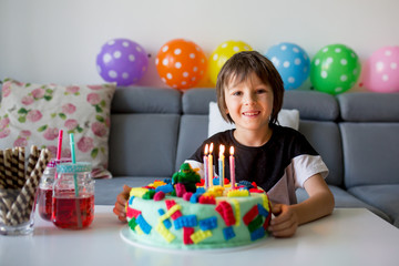 Cute child, boy, celebrating his birthday with colorful cake, candles, balloons