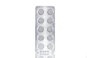 Packing white pills in a blister on white isolated background
