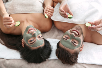 Obraz na płótnie Canvas Happy couple enjoying facial treatment procedure in spa salon, above view
