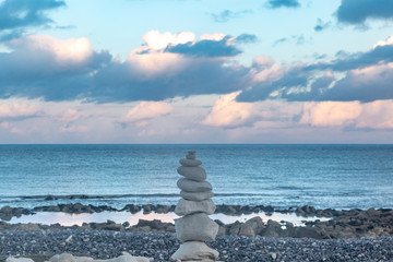 Fototapeta na wymiar A pile of zen rocks on a pebble beach in Sussex, with the ocean behind and an evening sky overhead