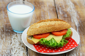 Healthy breakfast or lunch: brown cheese sandwich with lettuce and tomato with glass of fresh milk