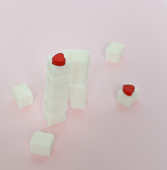 White sugar cubes on a pink background. What are the concepts of diabetes and calorie intake The concept of heart disease. No sugar.
