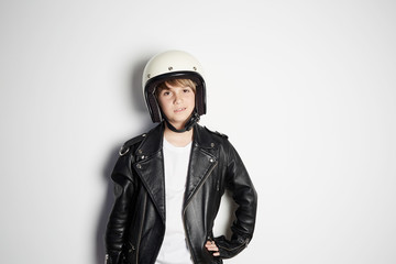 Portrait of Young cool beautiful teen kid in black leather jacket and white moto helmet smiling on white background
